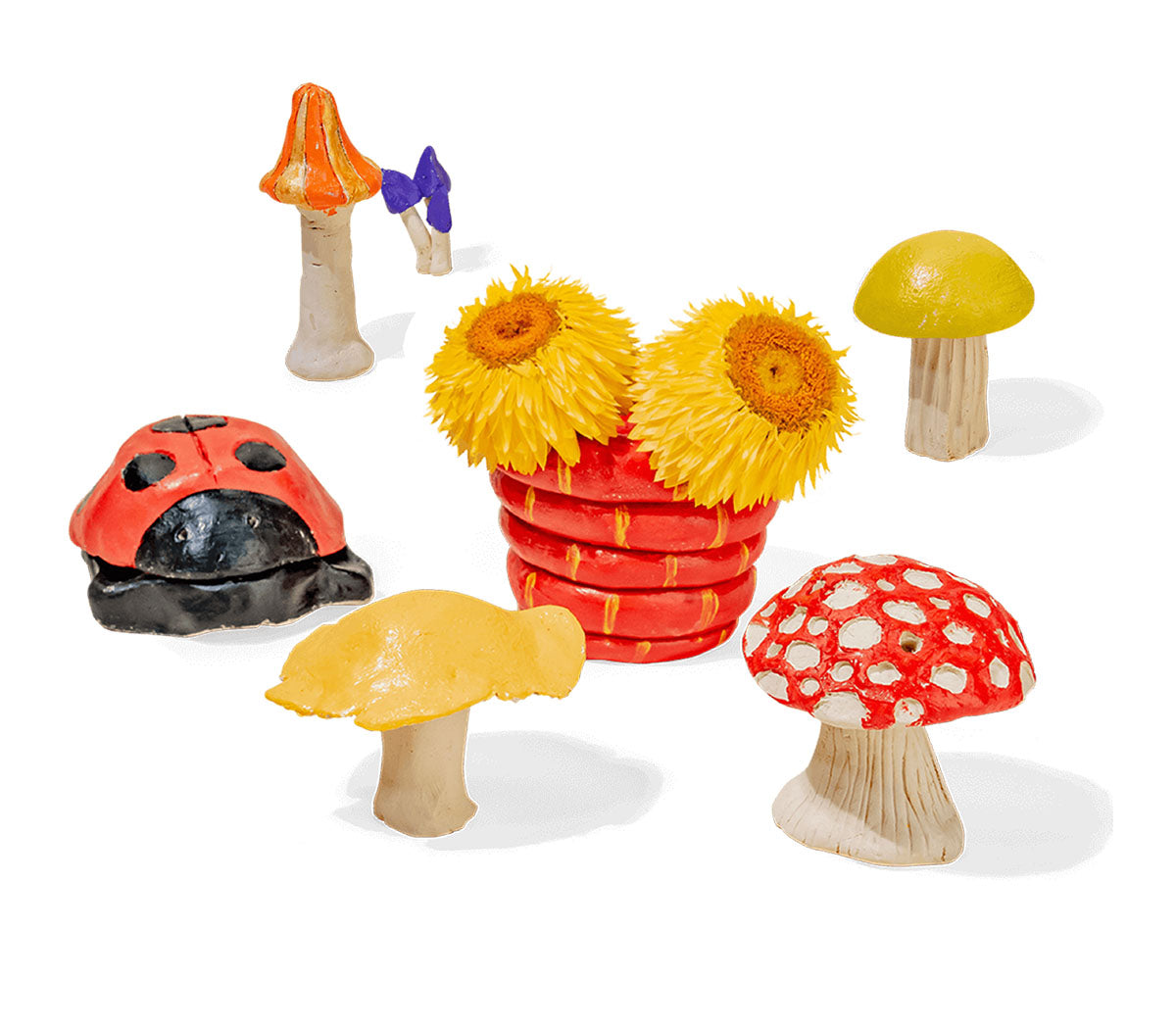 A whimsical clay scene featuring colorful mushrooms, a ladybug, and a coiled red snake planter with bright yellow flowers made from Sculpd Kids Pottery Kit