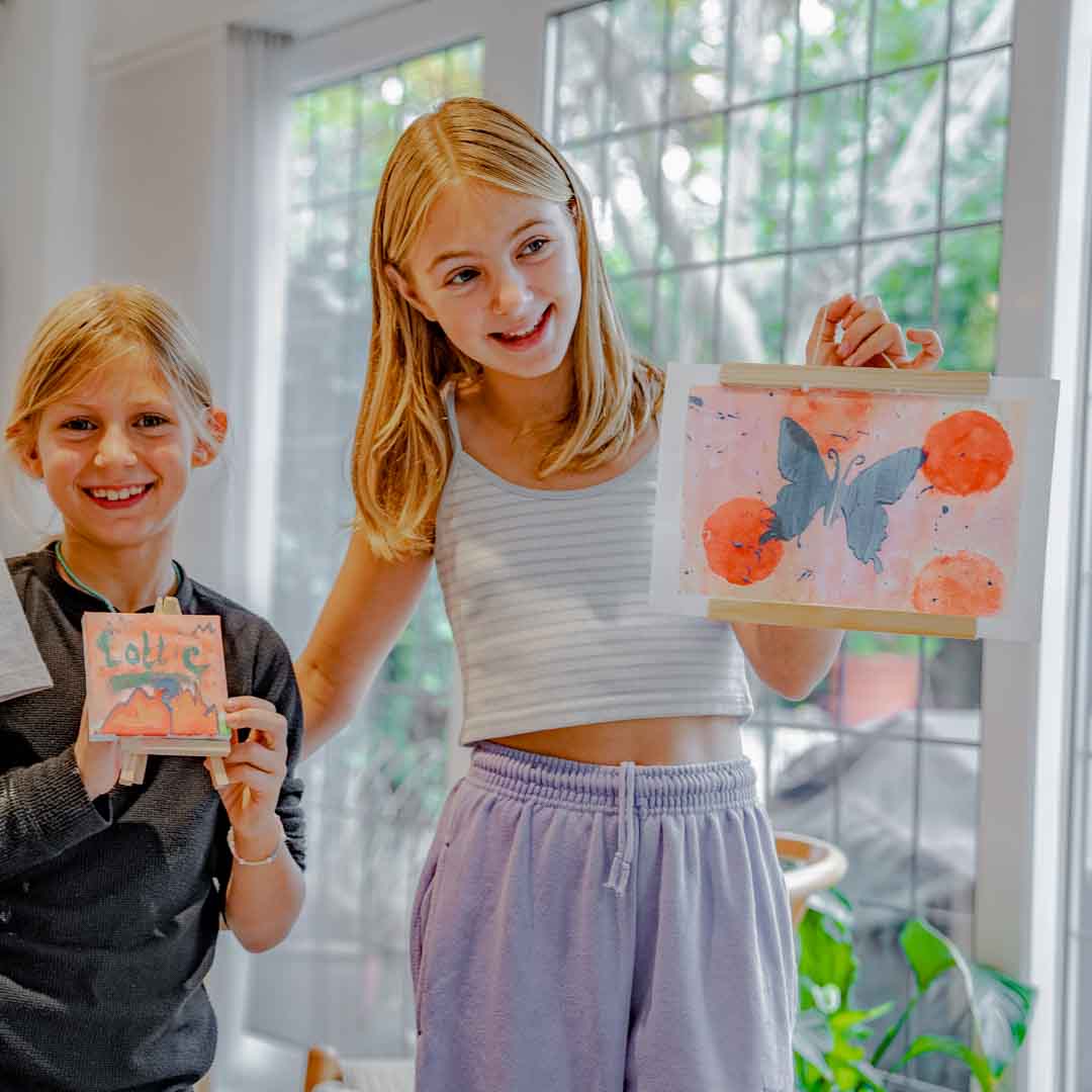 Two girls holding their finished Sculpd canvas paintings in front of them
