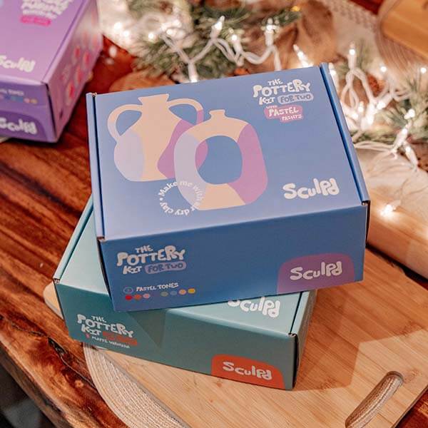 Sculpd Pottery Kit For Two boxes displayed on a cozy, holiday themed table
