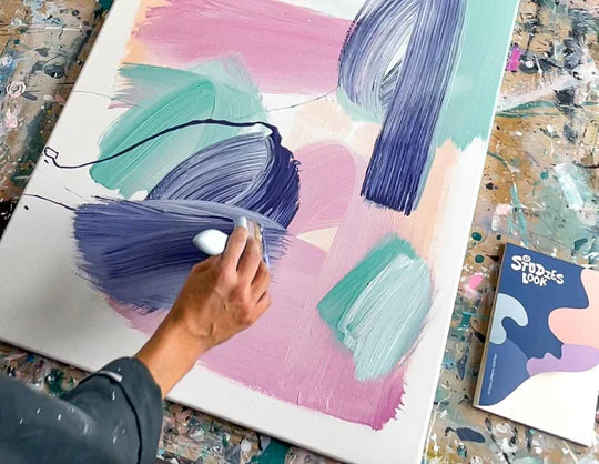 Man leaned over a table, painting on a canvas using Sculpd Canvas Painting Kit