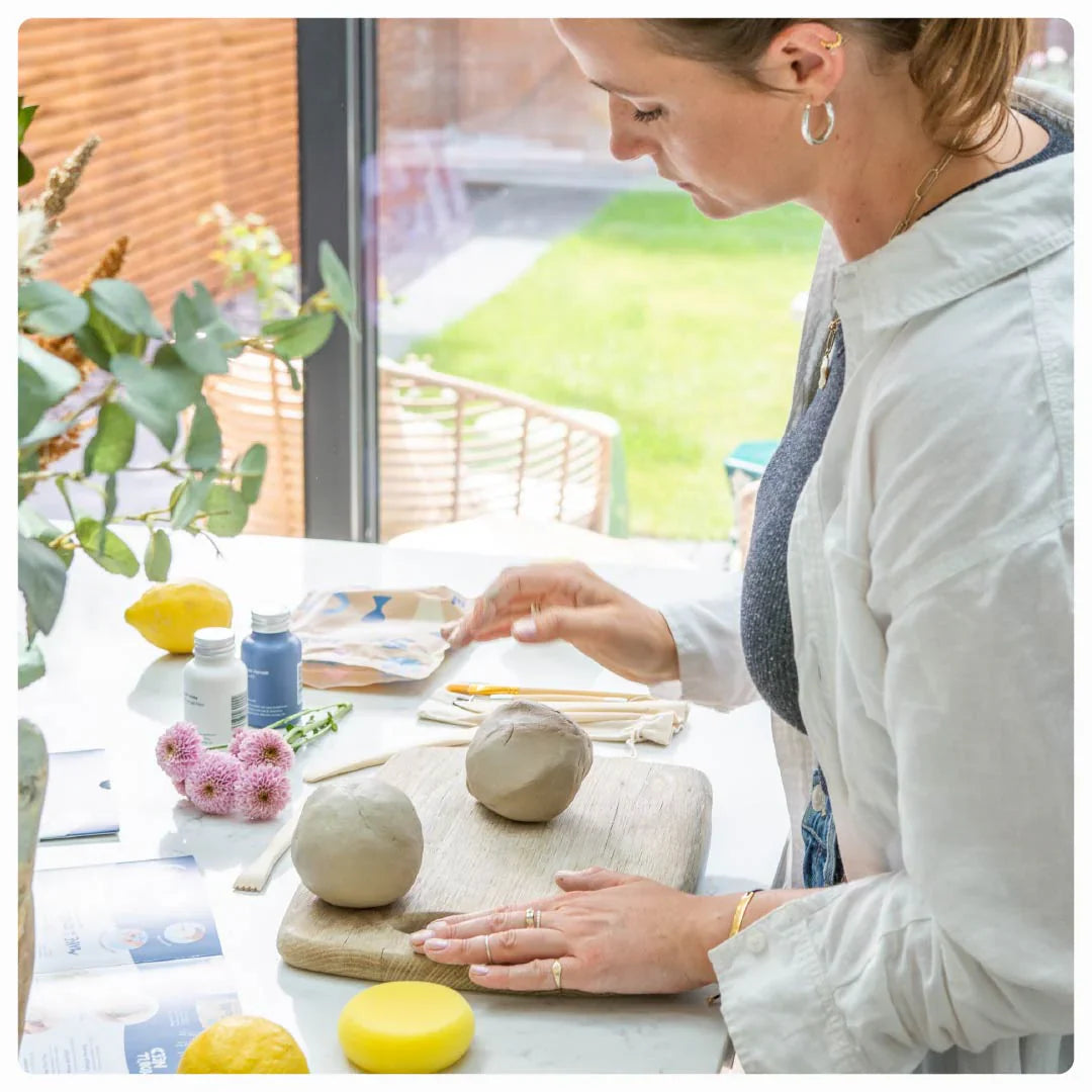 Woman demonstrating pottery techniques, with Sculpd tools and clay displayed on a table